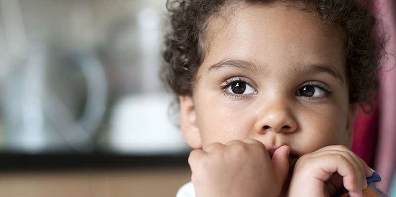 Royalty free stock photo of 3 years old child. She has her arms crossed under her chin and over her mouth. Without looking at camera, she has a very thoughtful expression.